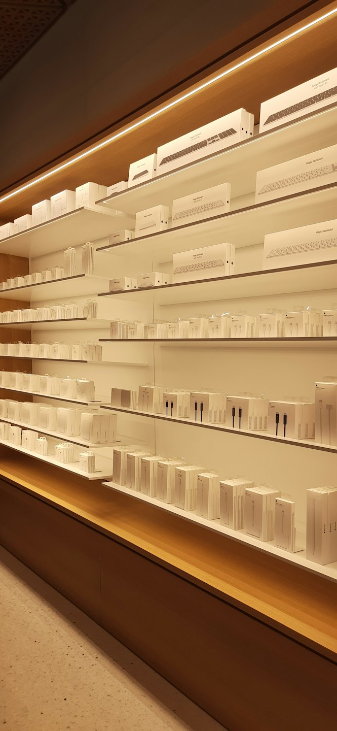 Electronic accessories neatly displayed on white shelves in a modern store.